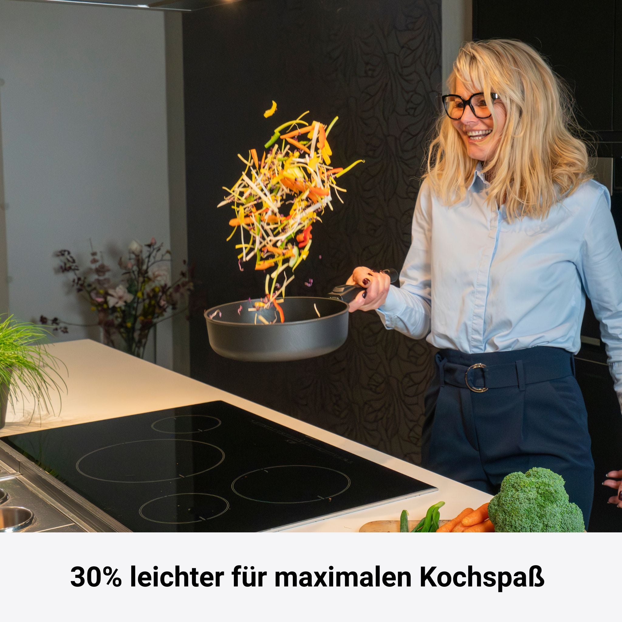 Hohe Edelstahlpfanne mit abnehmbarem Griff und Gemüse im Wurf über Herdplatte.