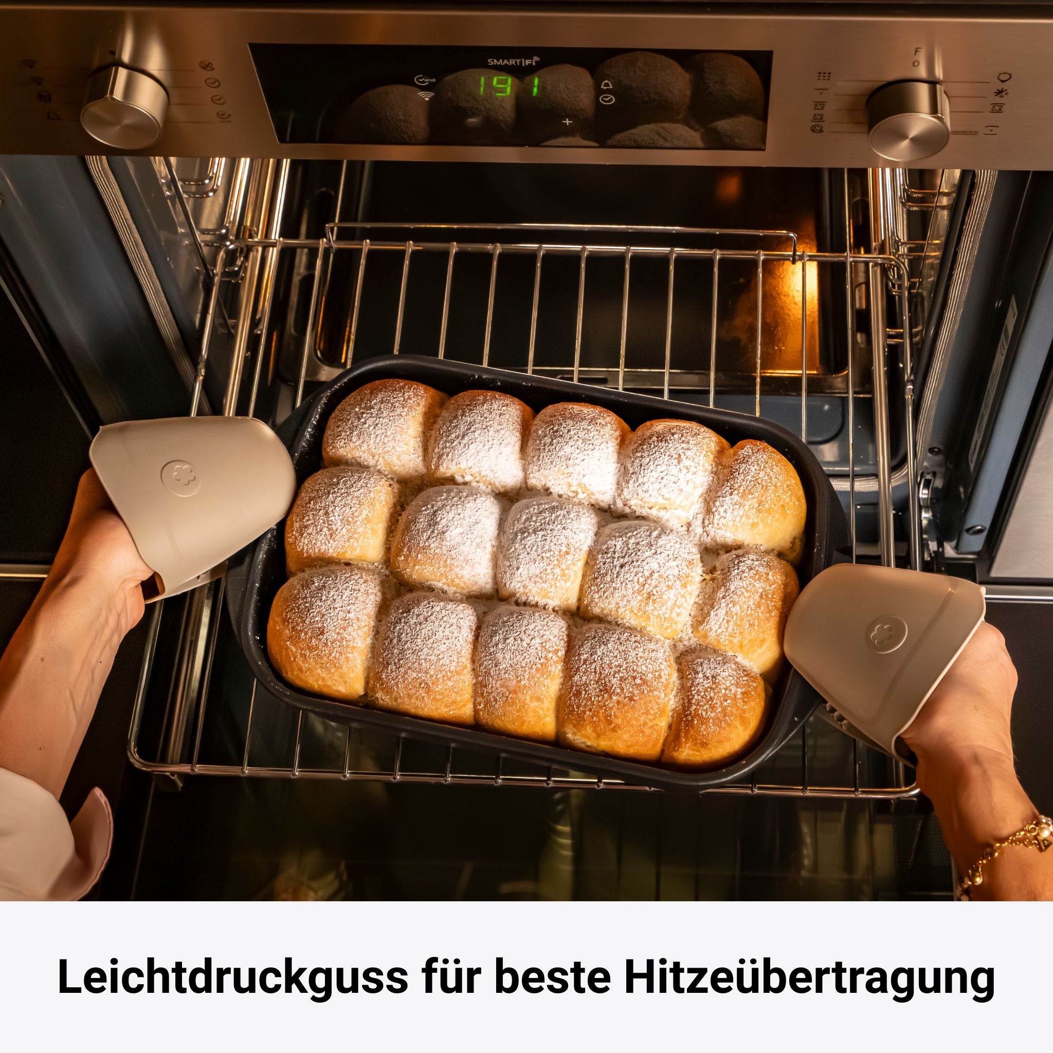 Backblech mit gebackenen, mit Puderzucker bestäubten Brötchen im Ofen, schwarze Oberfläche.