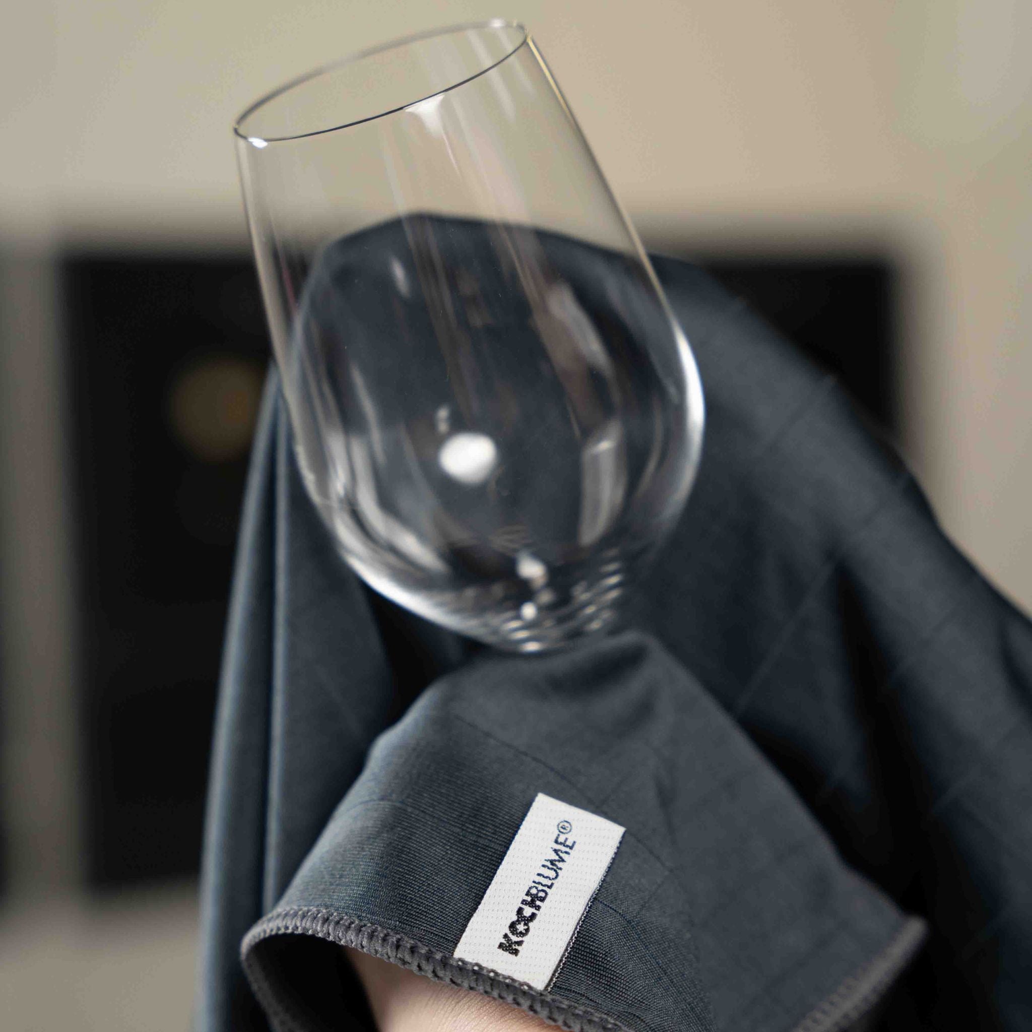 Anthrazitfarbenes Poliertuch mit Label, Glas zum Polieren darauf gestellt.