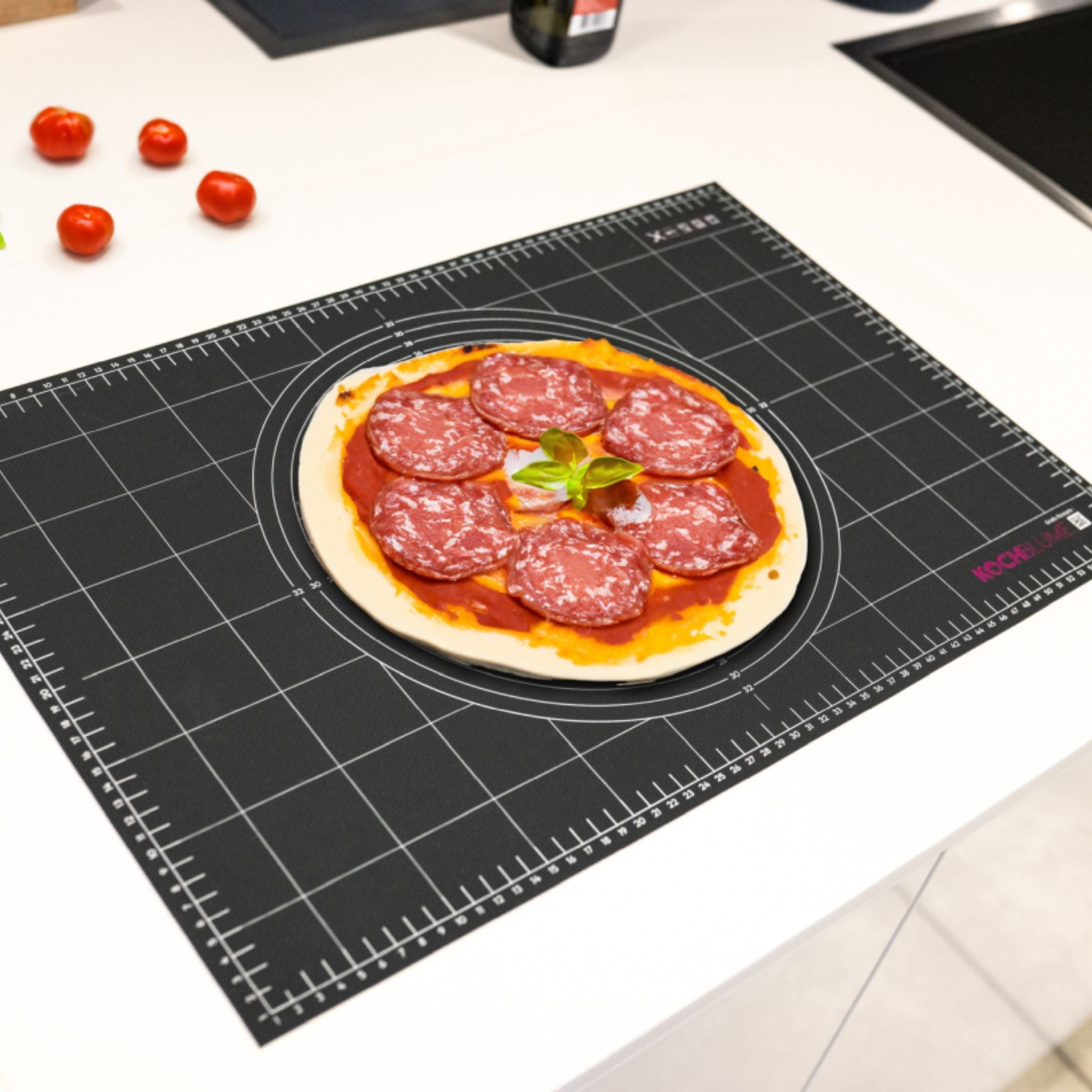 Schwarze Gewebematte mit Rastermuster und aufliegender Pizza mit Salami und Basilikum.