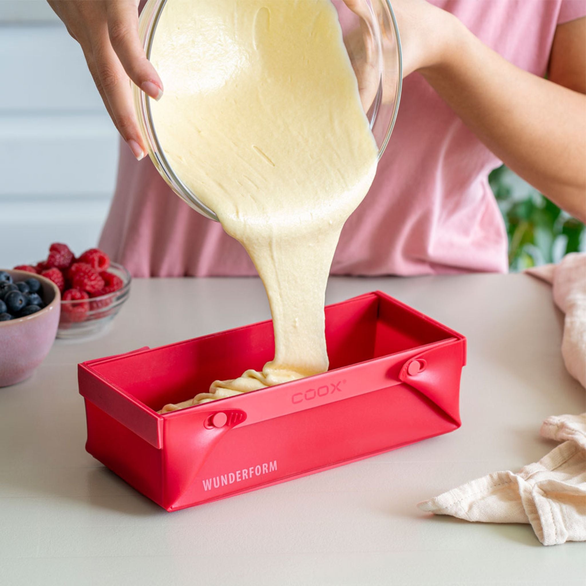 Rote rechteckige Silikonbackform mit Teigfüllung, beschriftet mit Coox-Wunderform.