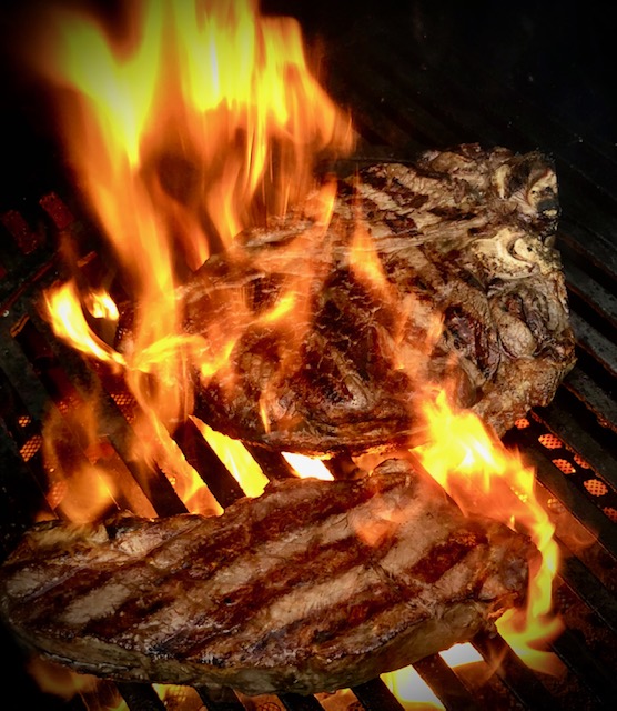 Steak auf dem Grill mit einer Flamme.