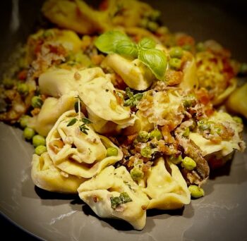 Tortellini in einer Auflaufform von Pfannen Harecker im Ofen zubereitet und mit Erbsen, Karotten und gekochtem Schinken verfeinert.