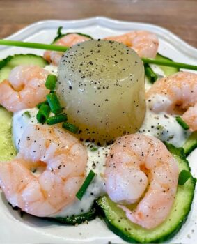 Erfrischendes Gurkengelee mit cremigem Joghurt und gekochtem Shrimps auf dekorativem Teller serviert.