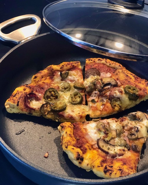 Pizza in einer Pfanne mit Deckel zum aufwärmen.