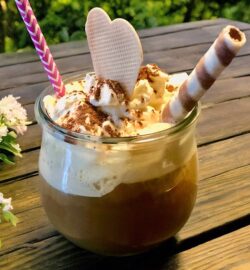 Eiskaffee veredelt mit Vanilleeis, Milch, Sirup und Sahne, dekorativ im Glas serviert.