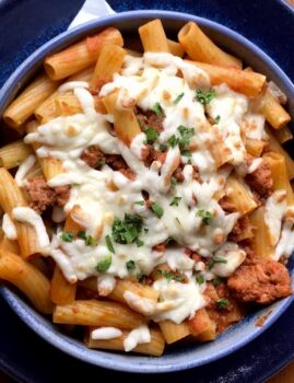 Rigatoni al forno mit Ragout aus Salsiccia auf einem Teller angerichtet.