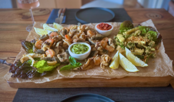 Frittierte Meeresfrüchte mit Gemüse auf einem großen Holzbrett serviert.