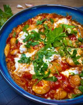 Gebackene Bohnen in Tomatensauce, in einer Schale mit frischer Petersilie garniert.