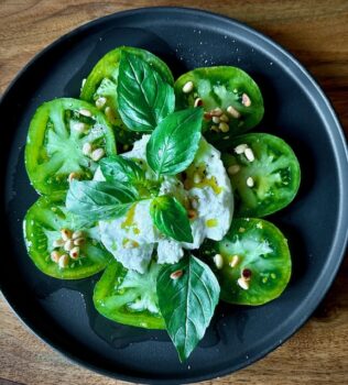 Zebra Caprese (Tomatensalat Caprese) mit gerösteten Pinienkernen und frischem Basilikum garniert.