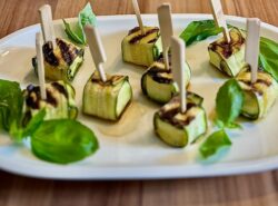 Zucchini-Feta-Päckchen mit Basilikumblättern auf einem weißen Teller angerichtet.