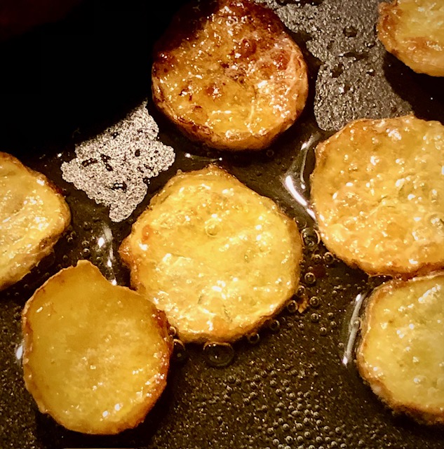 Ein paar Scheiben knuspriger Kartoffelchips in einer Pfanne.