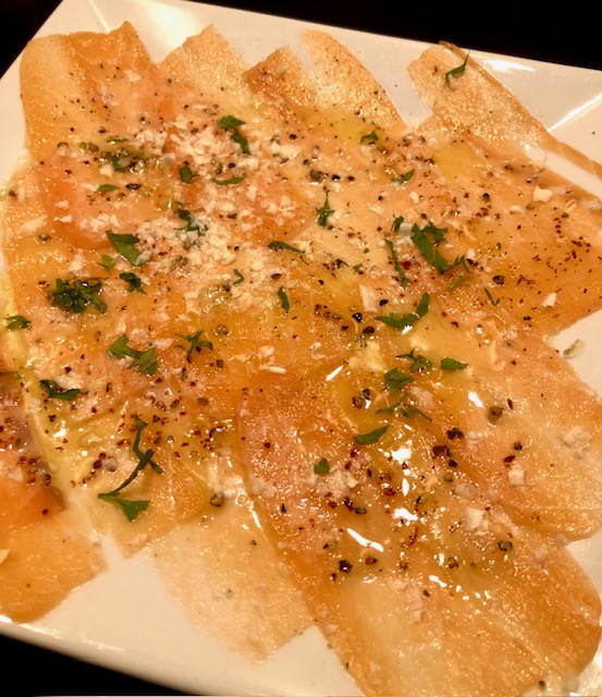 Leckere Scheiben eines Lachs Carpaccio auf einem Teller.