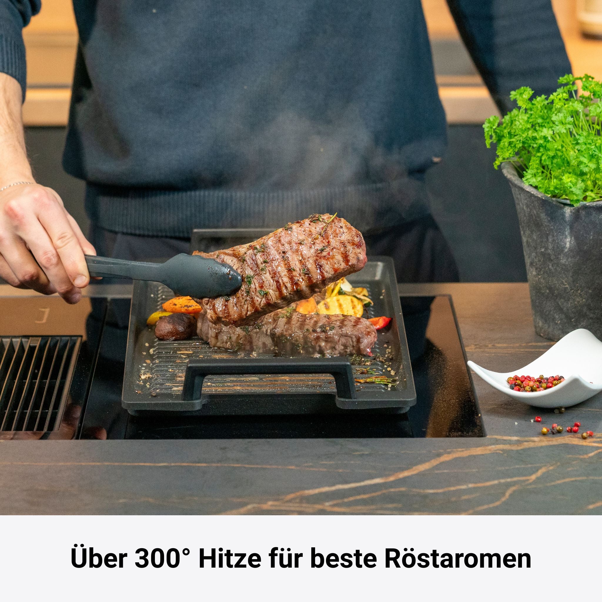 Schwarze Hochrandpfanne X-Lite mit erhitztem Steak und Gemüse auf Herdplatte.
