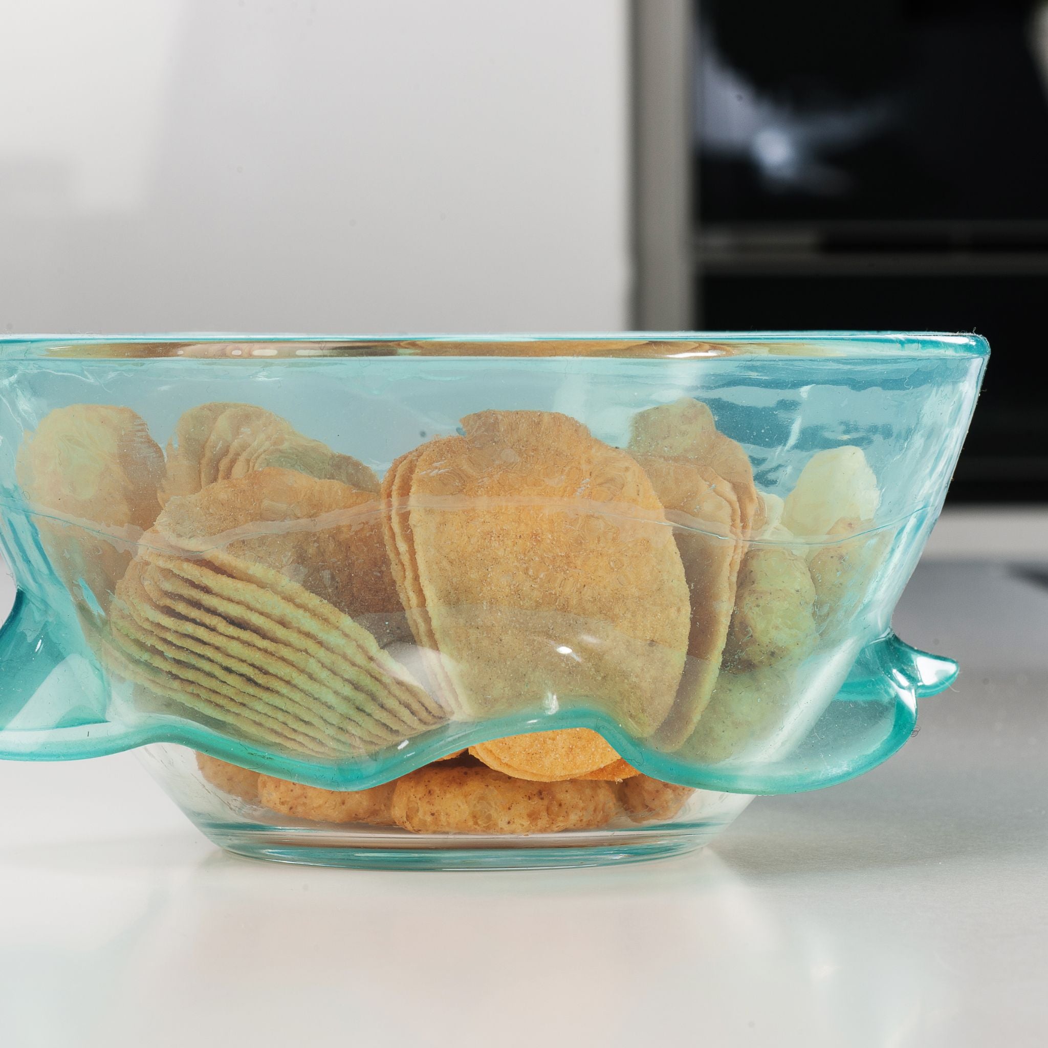 Transparente, wellenförmige glasschale mit türkisfarbenem rand, gefüllt mit keksen.