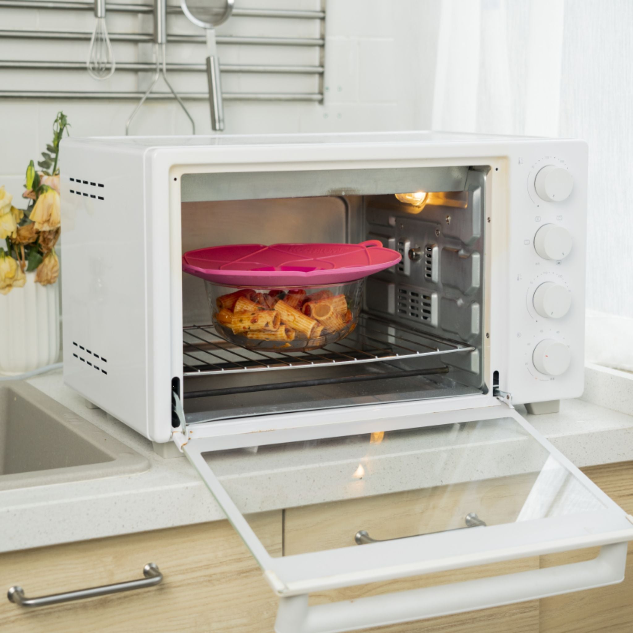 Anthrazitfarbene Kochblume als Deckel auf Backofen mit frisch gebackenem Gebäck darunter.