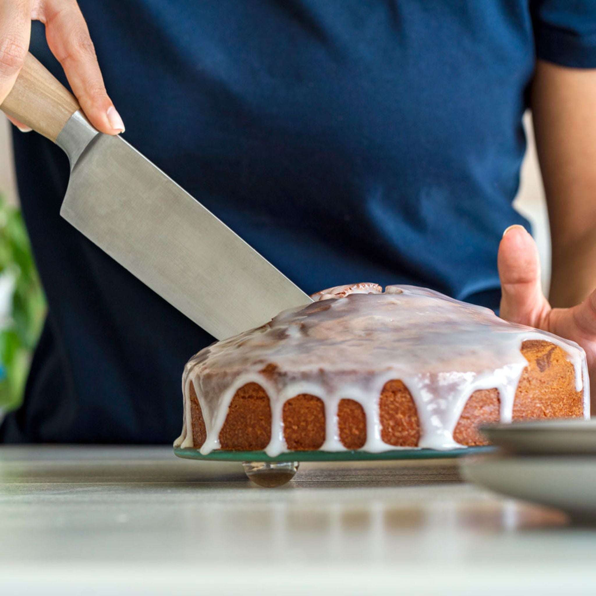 Springform mit abnehmbarem Rand, blauer Außenrand, glasierter Kuchen mit Zuckerglasur wird angeschnitten.